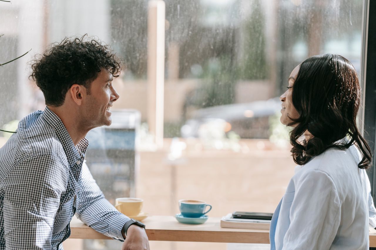 hero-img Two colleagues conversing over coffee by a window, enjoying a relaxed break indoors.